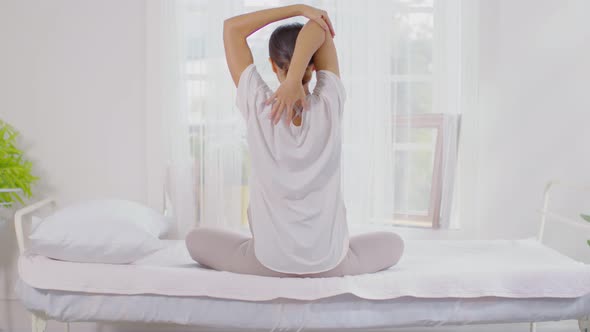 Calm of wellness Asian young woman sit on bed breathing and stretching before do yoga alt