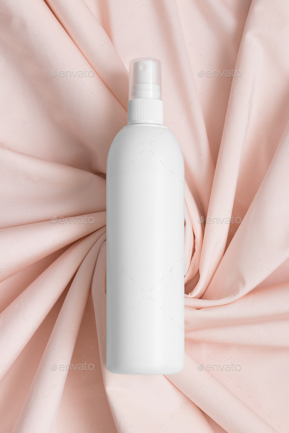 White cosmetic spray bottle mockup on the soft pink textile.