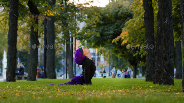 Muslim islamic woman practice yoga sun salutation in park on grass morning routine up facing dog