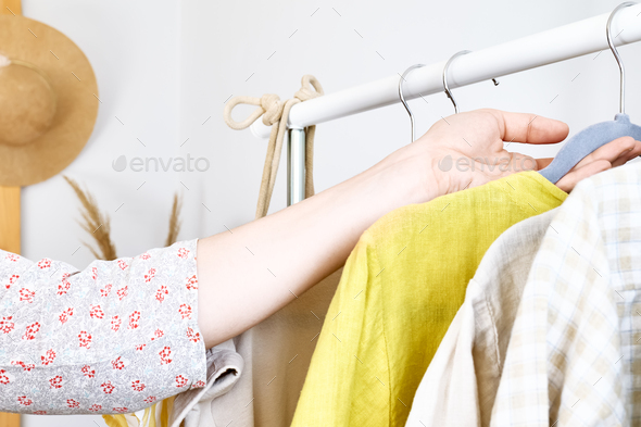 Woman takes linen dress on hanger from clothes rack. Slow Fashion. Sustainable seasonal Sale concept