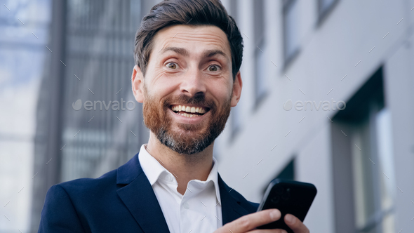 Close-up joyful man holding phone receiving email reading incredible news enthusiastic businessman