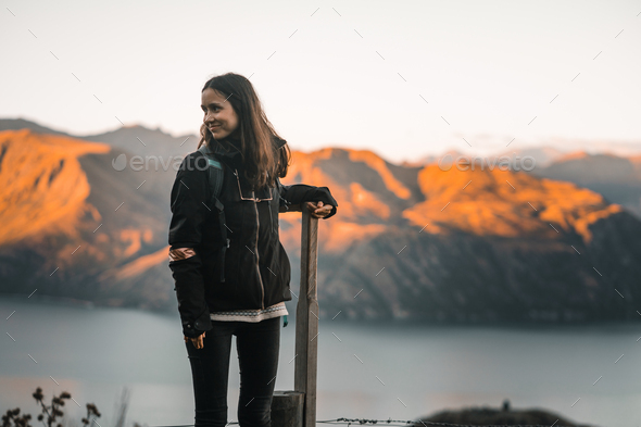 young caucasian brunette woman with loose straight hair black jacket black pants standing leaning on