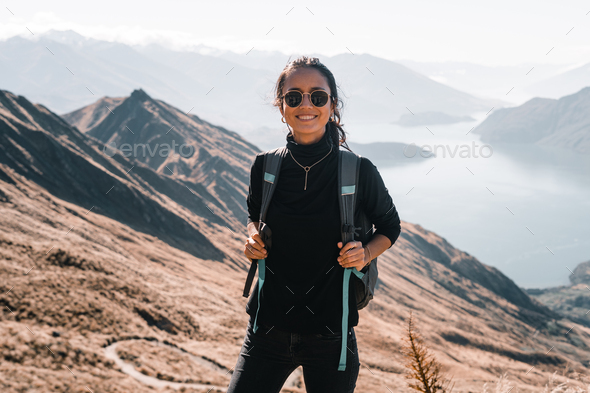 brunette caucasian young woman with a backpack on her back black t-shirt black pants and sunglasses