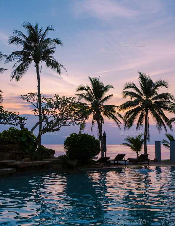 Tropical swimming pool with palm trees during sunset Stock Photo by ...