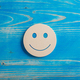 Smiling face expression cut into a wooden circle placed over blue background - PhotoDune Item for Sale