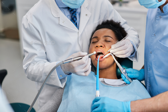 African American woman visiting dentist and having dental drill procedure at the clinic.