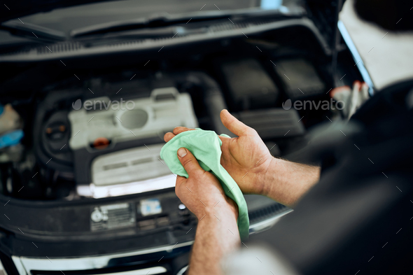 Close-up of mechanic cleaning hands after working on car engine in a workshop.