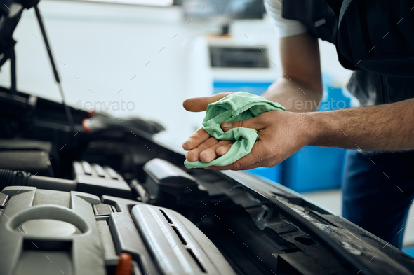 Close-up of mechanic cleaning his hands after repairing car engine in a workshop.