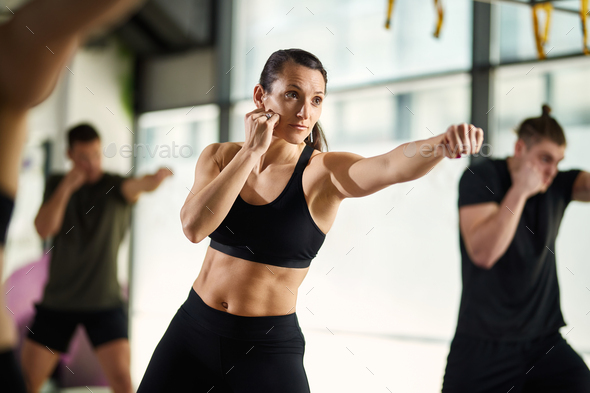 Young sportswoman exercising hand punches during martial arts training at health club.
