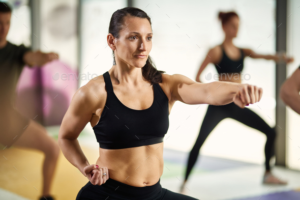 Athletic woman in fighting stance exercising hand punches on martial arts training at health club.