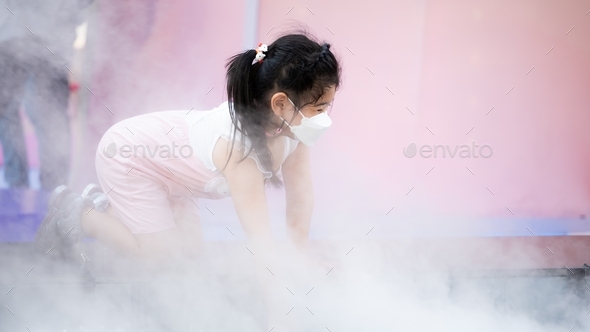 Cute kid girl wearing face mask, going on New Year's Eve holiday, child playing in mist or smoke.