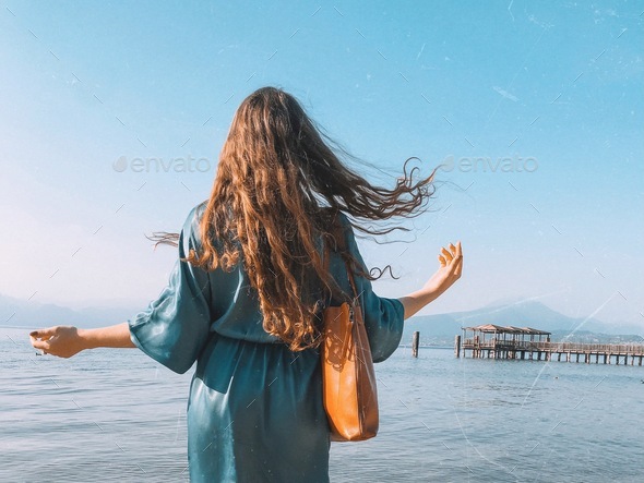 Woman on the beach, water, beautiful blue, windy hair, springtime, summer, lake, moments in nature  - Stock Photo - Images