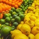 Three rows of citrus fruits cascading in market display with oranges, green limes, and yellow lemons - PhotoDune Item for Sale