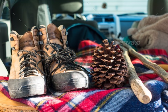 Hiking boots and walking sticks in the open trunk of an SUV packed for an outdoor adventure