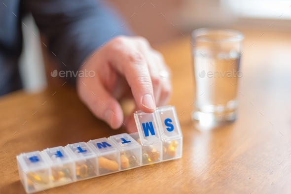 Man using a pill holder to organize daily supplements and medication