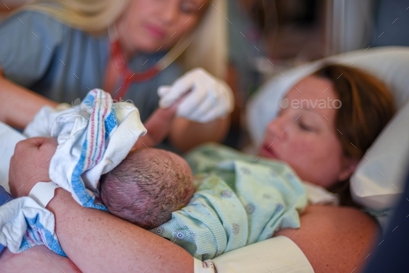 Young woman with newborn baby in labor and delivery room at hospital