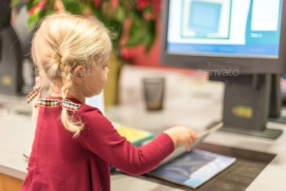 Young girl checking out library books using a computerized self checkout station
