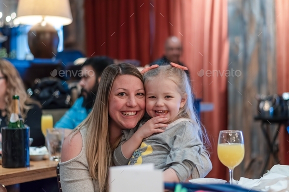 Happy mom and young daughter having brunch at a restaurant