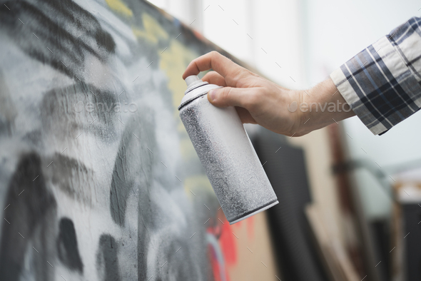 a hand holding spray paint can, artist doing graffiti art on the wall ...