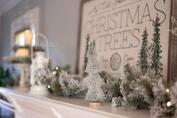 Flocked bottle brush trees and garland on a white fireplace mantel
