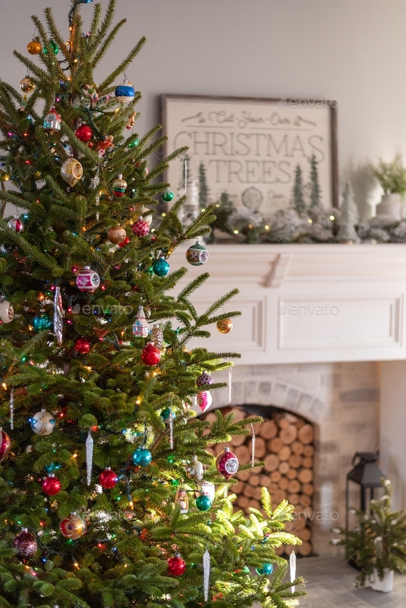 Live Christmas tree with vintage ornaments in front of a white fireplace mantel