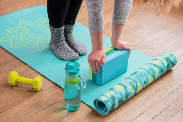 Woman using a yoga block to stretch during home workout