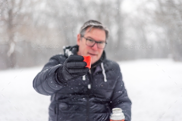 Man raising a red thermos cup to make a toast