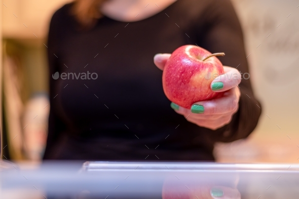 Woman reaching for an apple in the fridge making a healthy choice