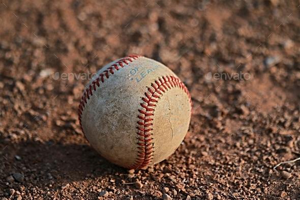 Single baseball near pitcher\'s mound at golden hour.