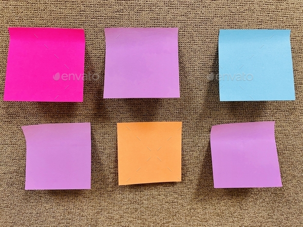 Colorful blank sticky notes on textured office divider.