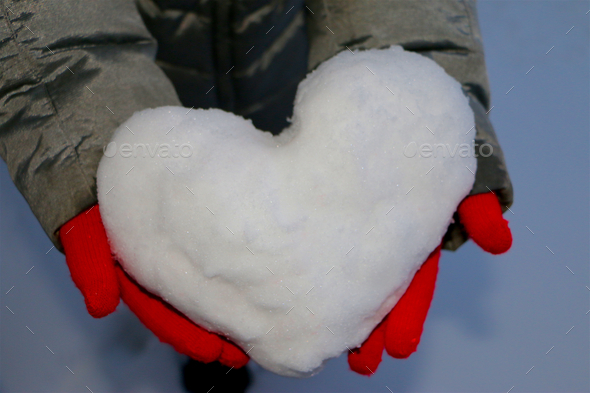 Closeup Image of Heart-Shaped Snowball held by red gloves hands.
