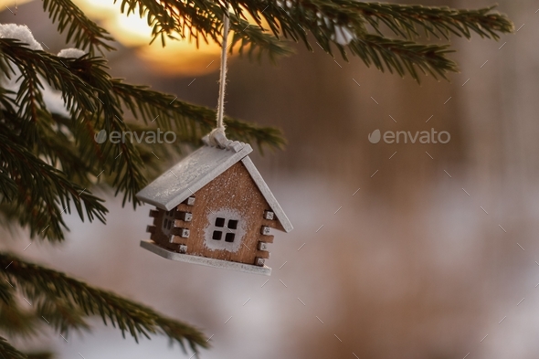 Christmas tree toy wooden house on a snow-covered Christmas tree. MINIMALIST HOLIDAY SEASON