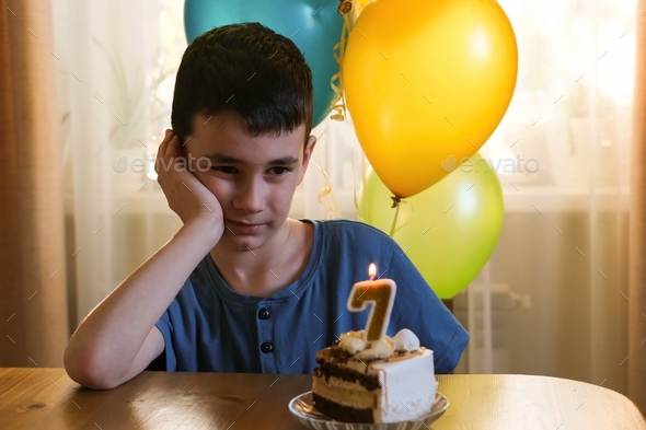 Birthday. The boy dreamily makes a wish and blows out the candles on the cake