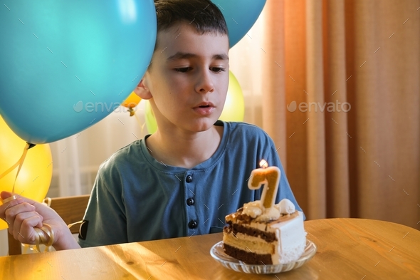 Birthday. Happy boy makes a wish and blows out the candles on the cake