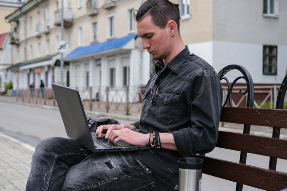 A young freelancer is working on a laptop in the city. Online business, freelance, remote work.