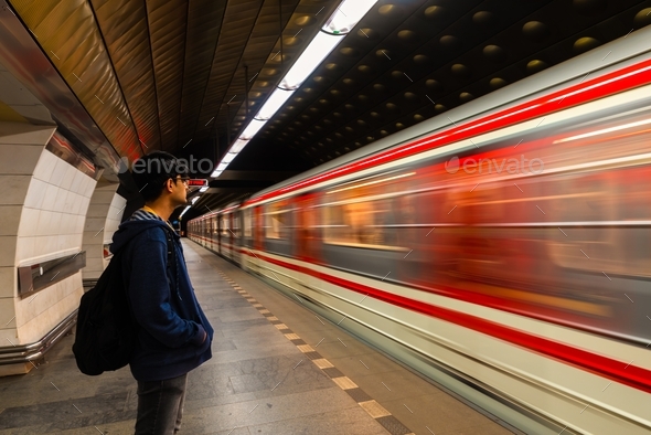 Fast moving train with motion blur and waiting traveler with a back pack at under ground station.