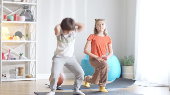 Wide Shot of Positive Active Caucasian Children Exercising at Home Indoors alt