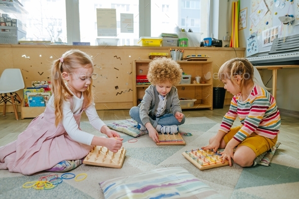Preschool students playing with geoboard wrapping rubber bands in kindergarten