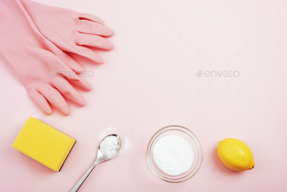 Cleaning gloves, yellow sponge, baking soda and lemon on pink background. Eco cleaning concept.