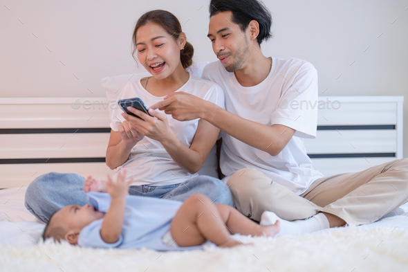 Mom and father use mobile phone enjoy online shopping baby happy laying ...