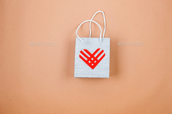 Red paper heart on beige paper background. Giving Tuesday,