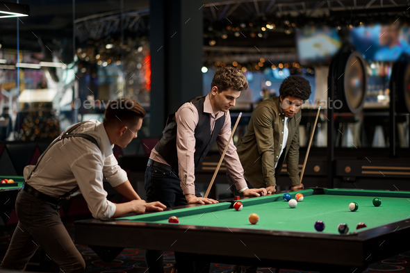 Company of handsome young guy playing in pool