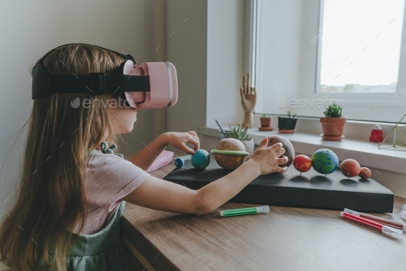 Little girl using VR glasses at home for learning Solar system planets