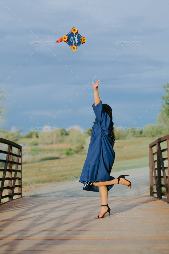 Young Girl throwing her cap in to the air after graduating from high ...