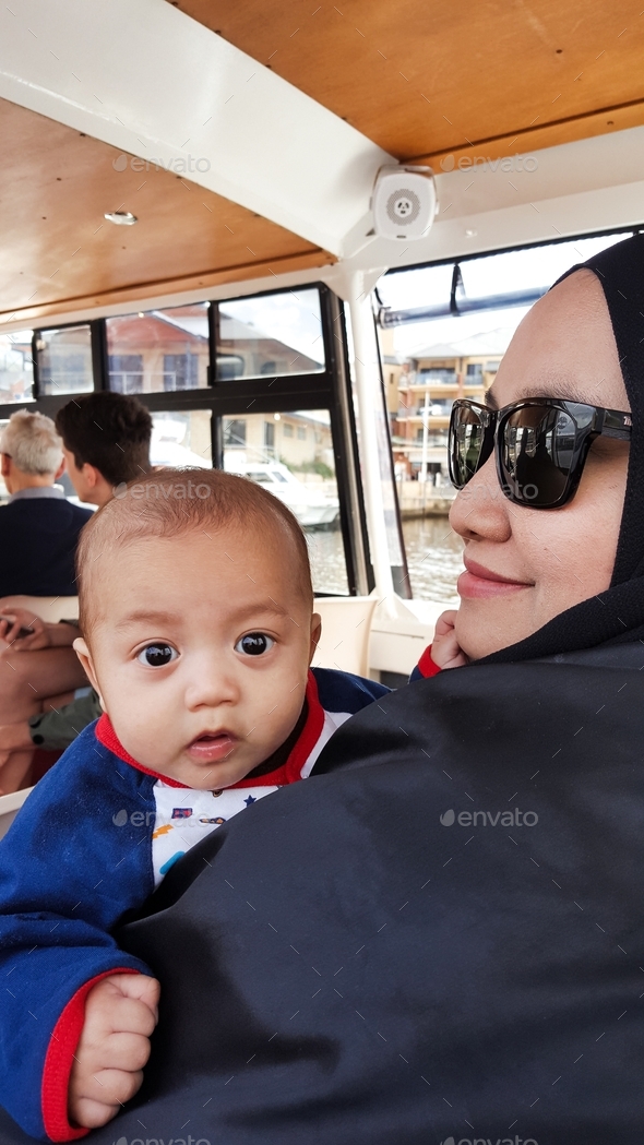 Mother wearing hijab and sunglasses holding 3 month old baby. Stock