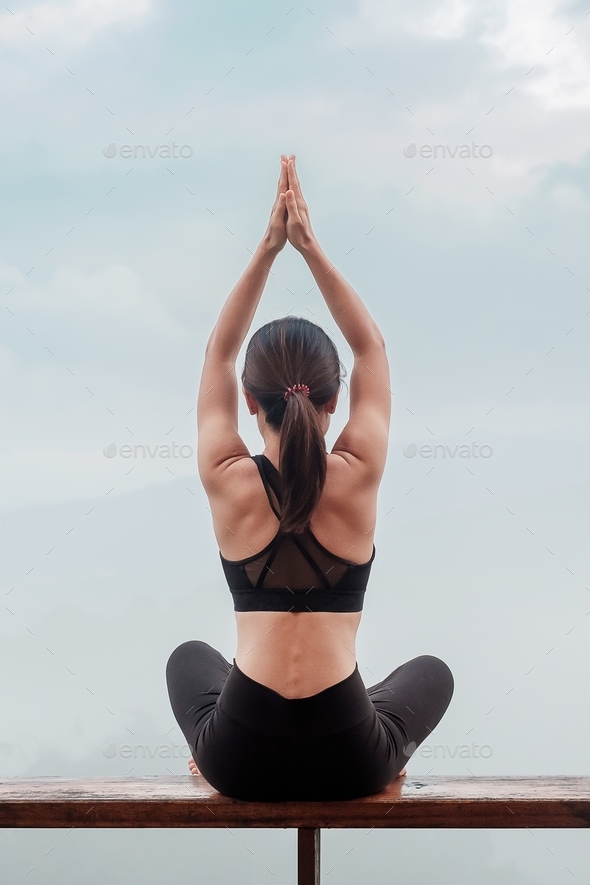 Young woman doing Yoga and stretching muscle in morning, healthy girl meditation against mountain