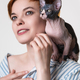 Sphynx kitten sitting on shoulder of happy redhead young woman. Selective focus on cat - PhotoDune Item for Sale