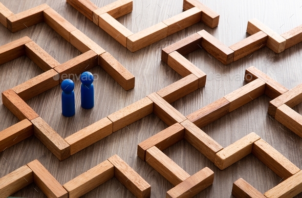 Wooden miniature at the start point of puzzle maze wood block. Leadership concept.