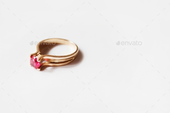 Golden ring with a red ruby on white background