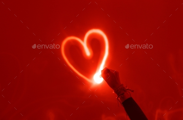 A girl drawing a heart with light on the red wall